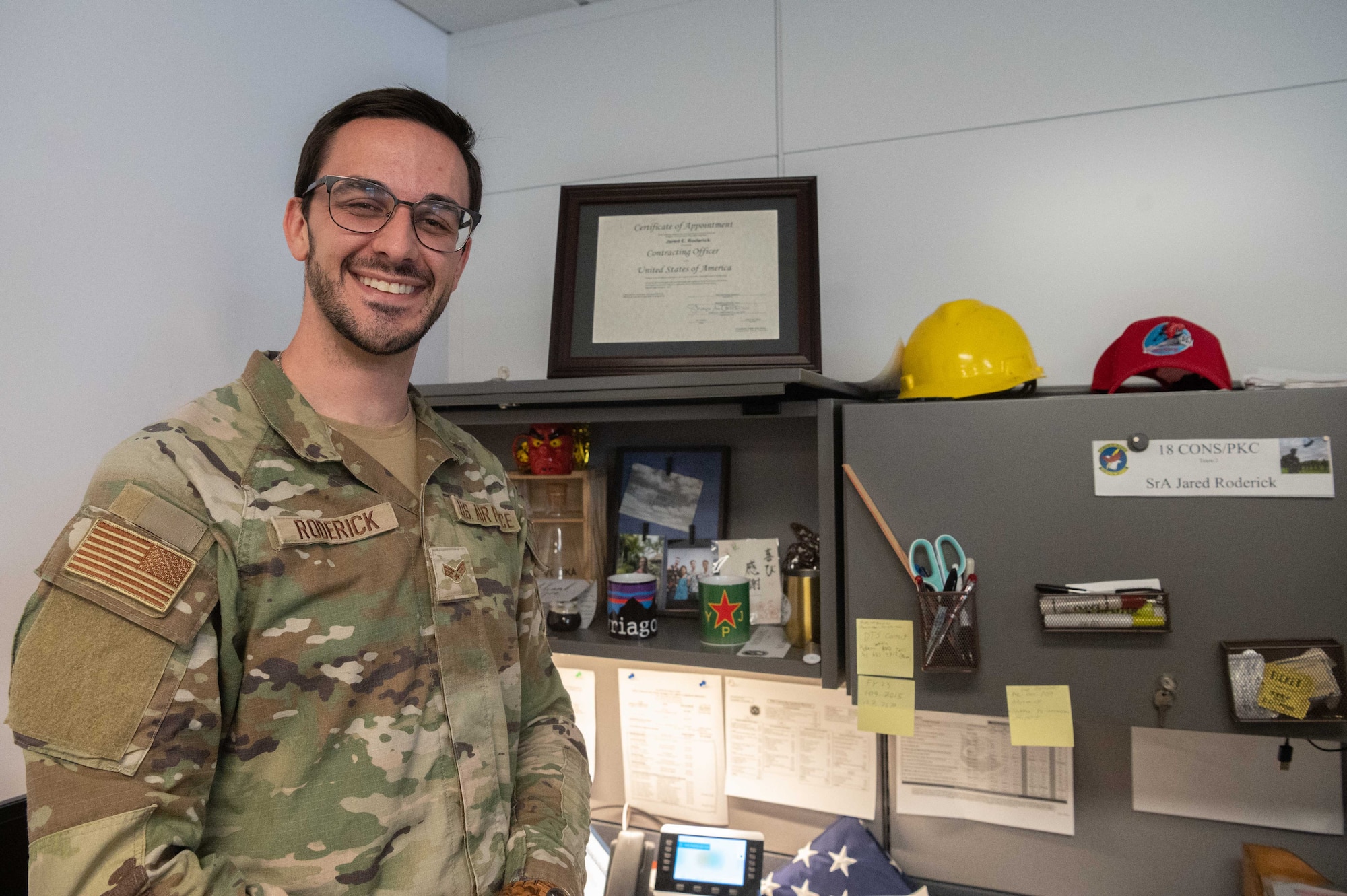 Airman smiles for a photo in front of his work station