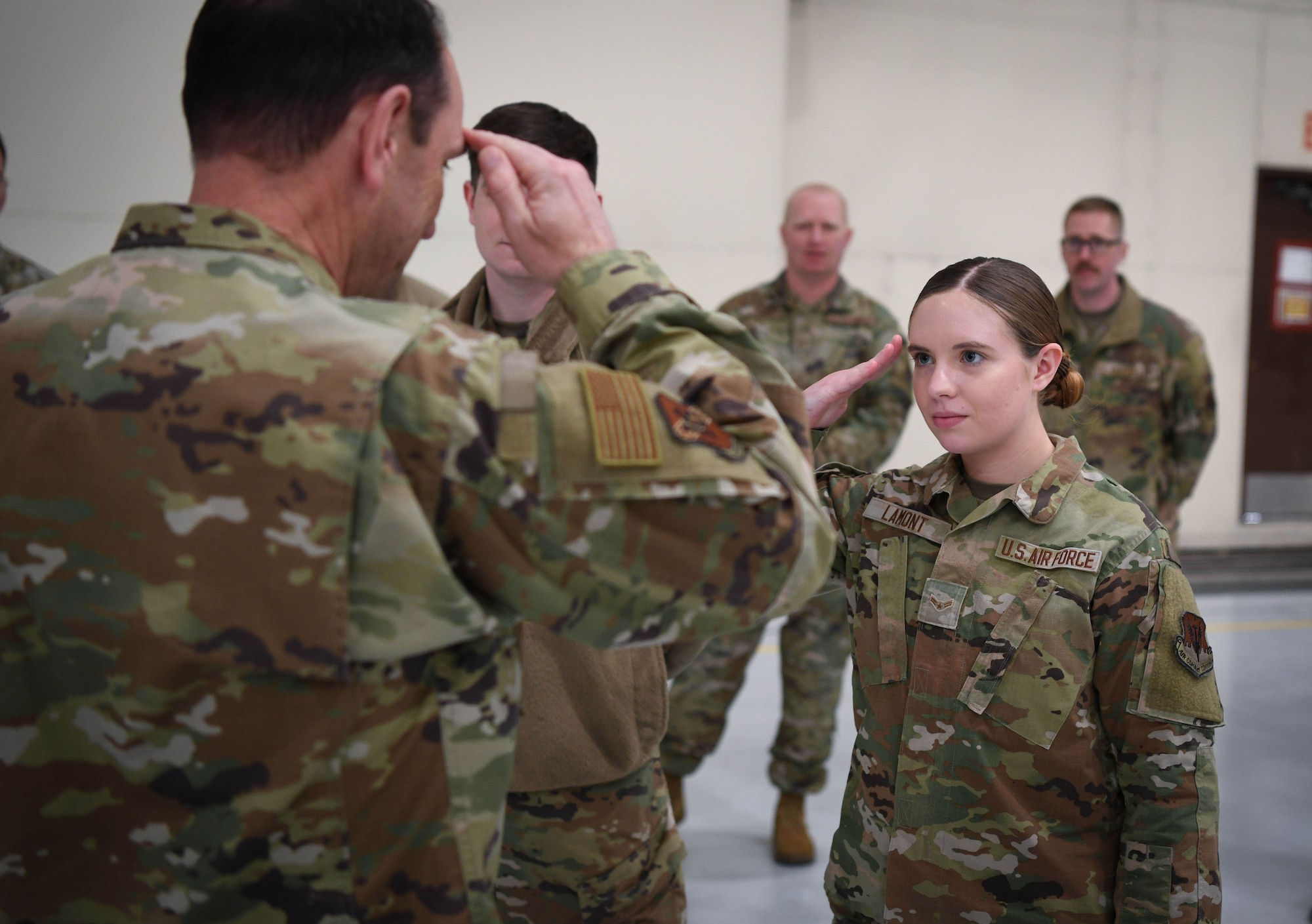Woman in green uniform salutes man in green uniform.