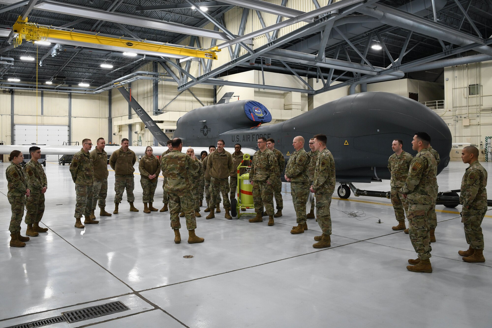 Group of people stand in aircraft hangar.
