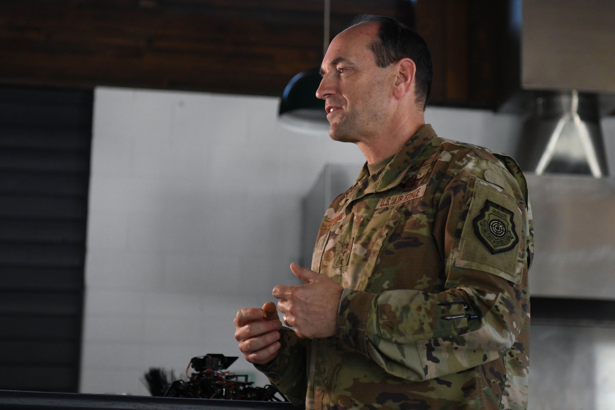 Man in green uniform talks while moving hands