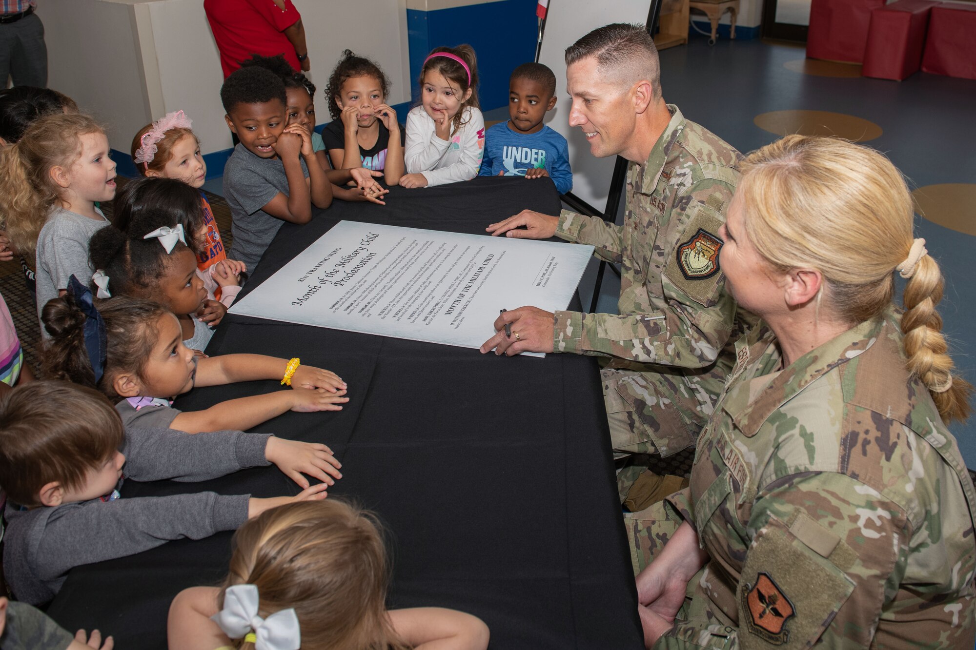 U.S. Air Force Col. Billy Pope, 81st Training Wing commander, and Chief Master Sgt. Sarah Esparza, 81st TRW command chief, interact with kids during the Month of the Military Child proclamation signing inside the Child Development Center at Keesler Air Force Base, Mississippi, March 31, 2023.