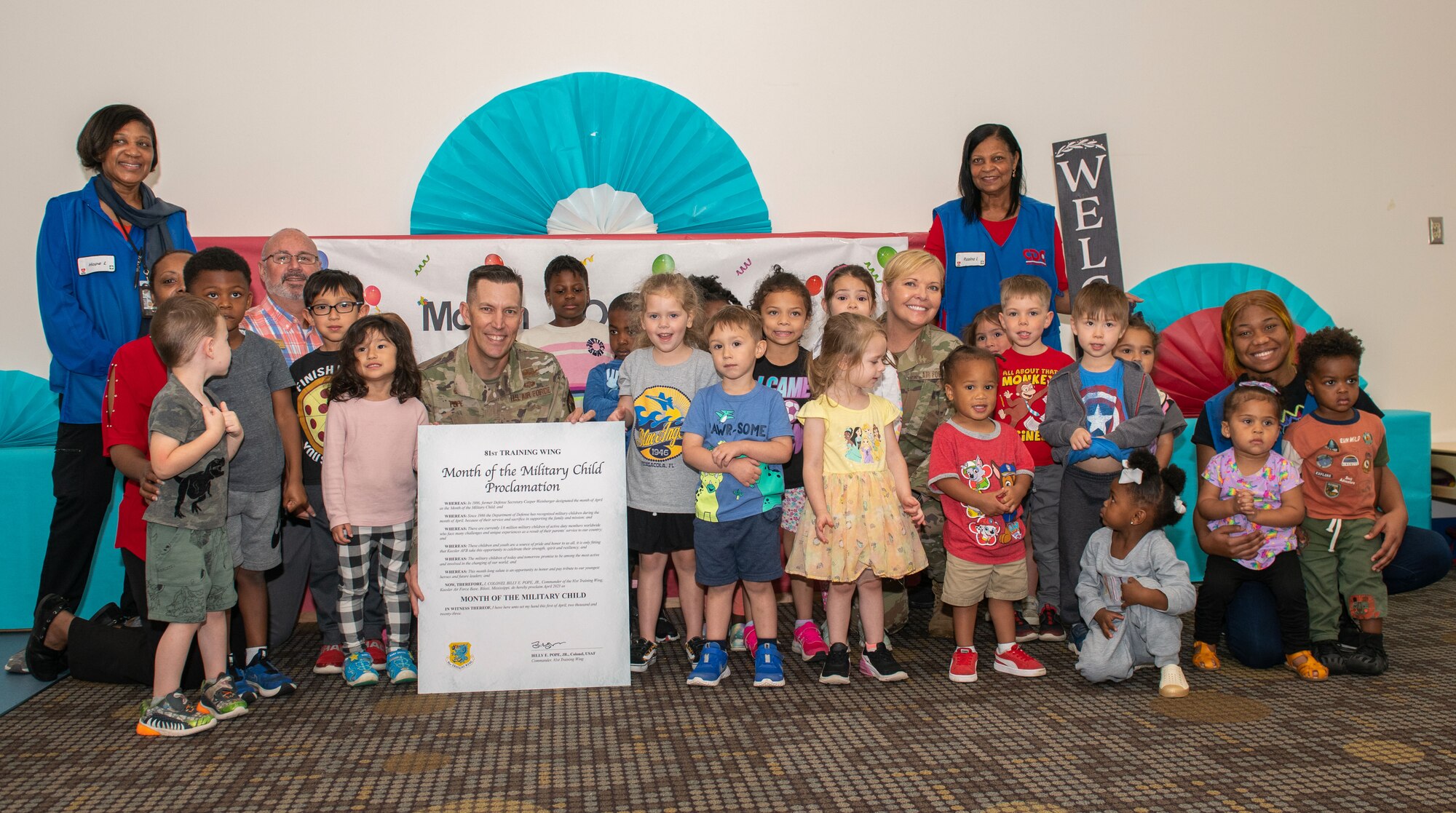 U.S. Air Force Col. Billy Pope, 81st Training Wing commander, and Chief Master Sgt. Sarah Esparza, 81st TRW command chief, pose for a photo with kids during the Month of the Military Child proclamation signing inside the Child Development Center at Keesler Air Force Base, Mississippi, March 31, 2023.