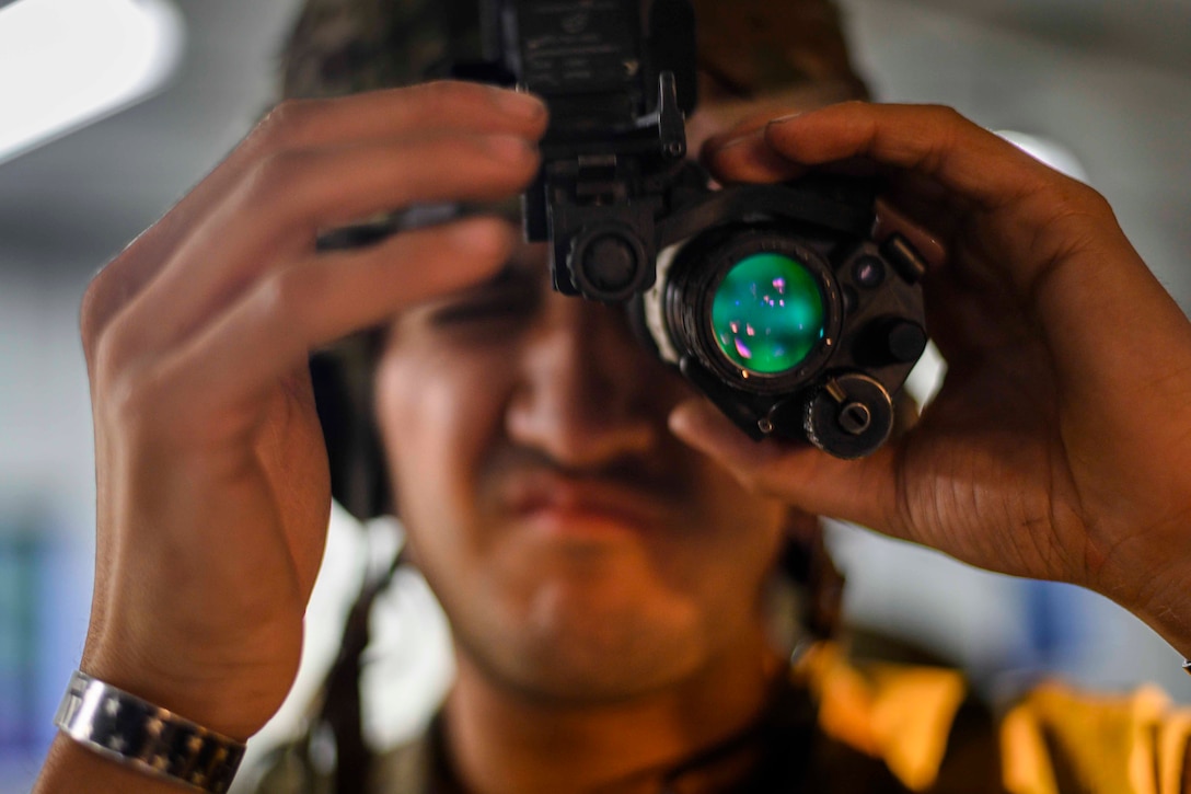 A soldier looks through night vision goggles.