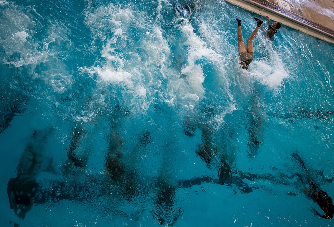 Service members swim in a pool.