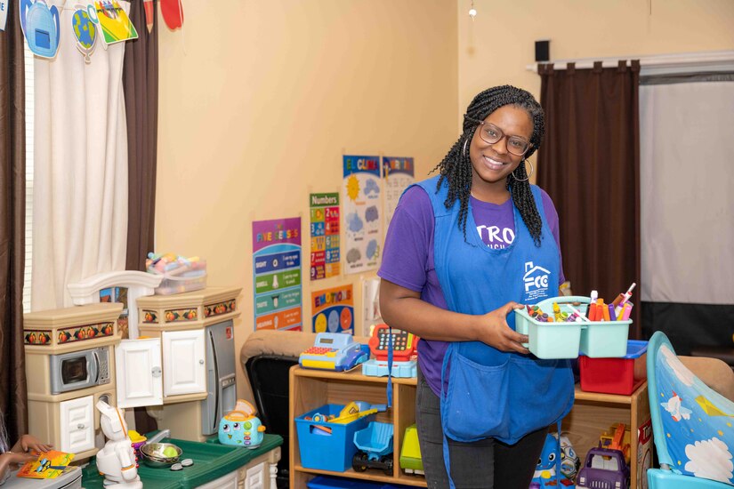 A woman poses for a picture surrounded by children's toys.