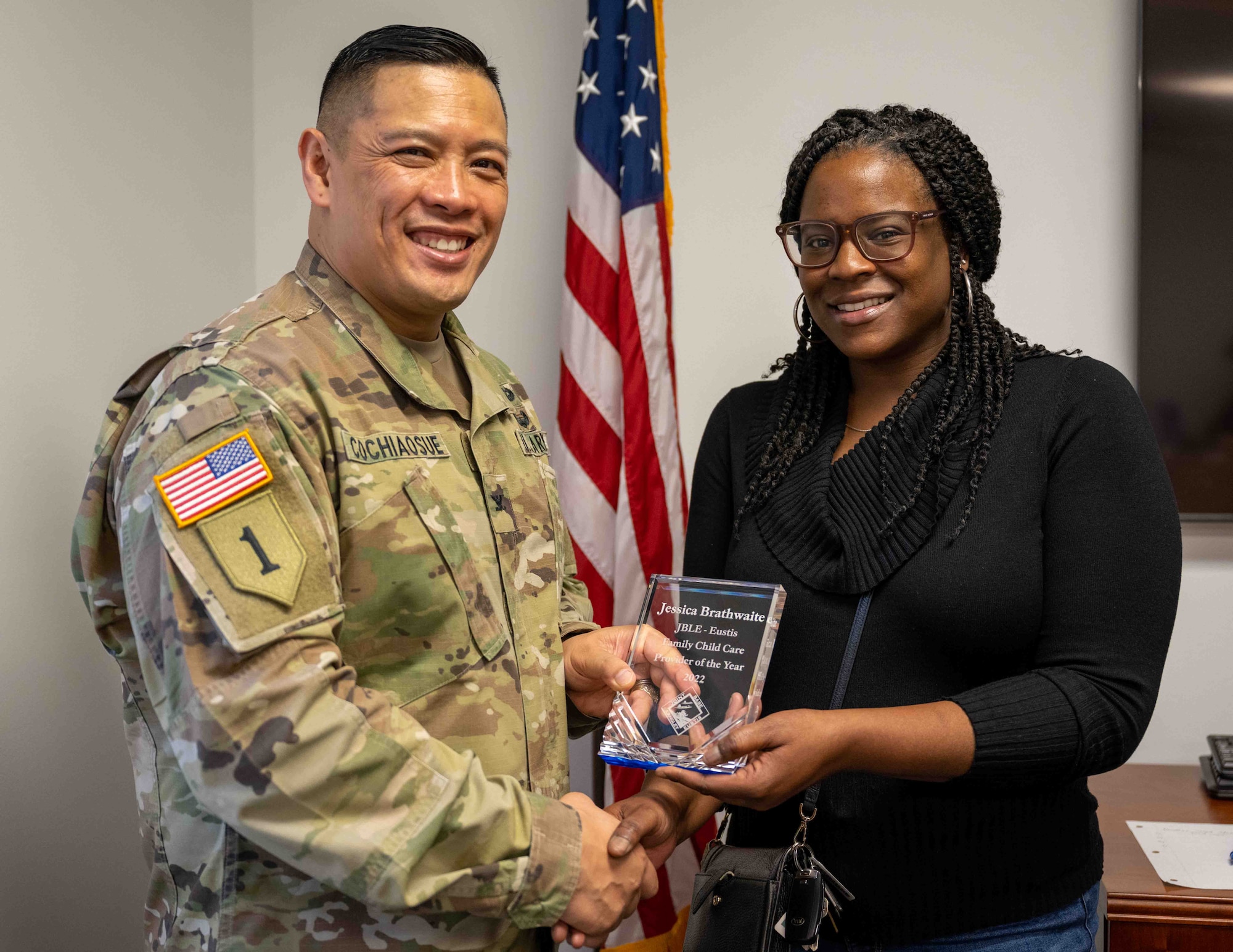 A woman accepts an award from a U.S. army officer.