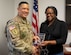 A woman accepts an award from a U.S. army officer.