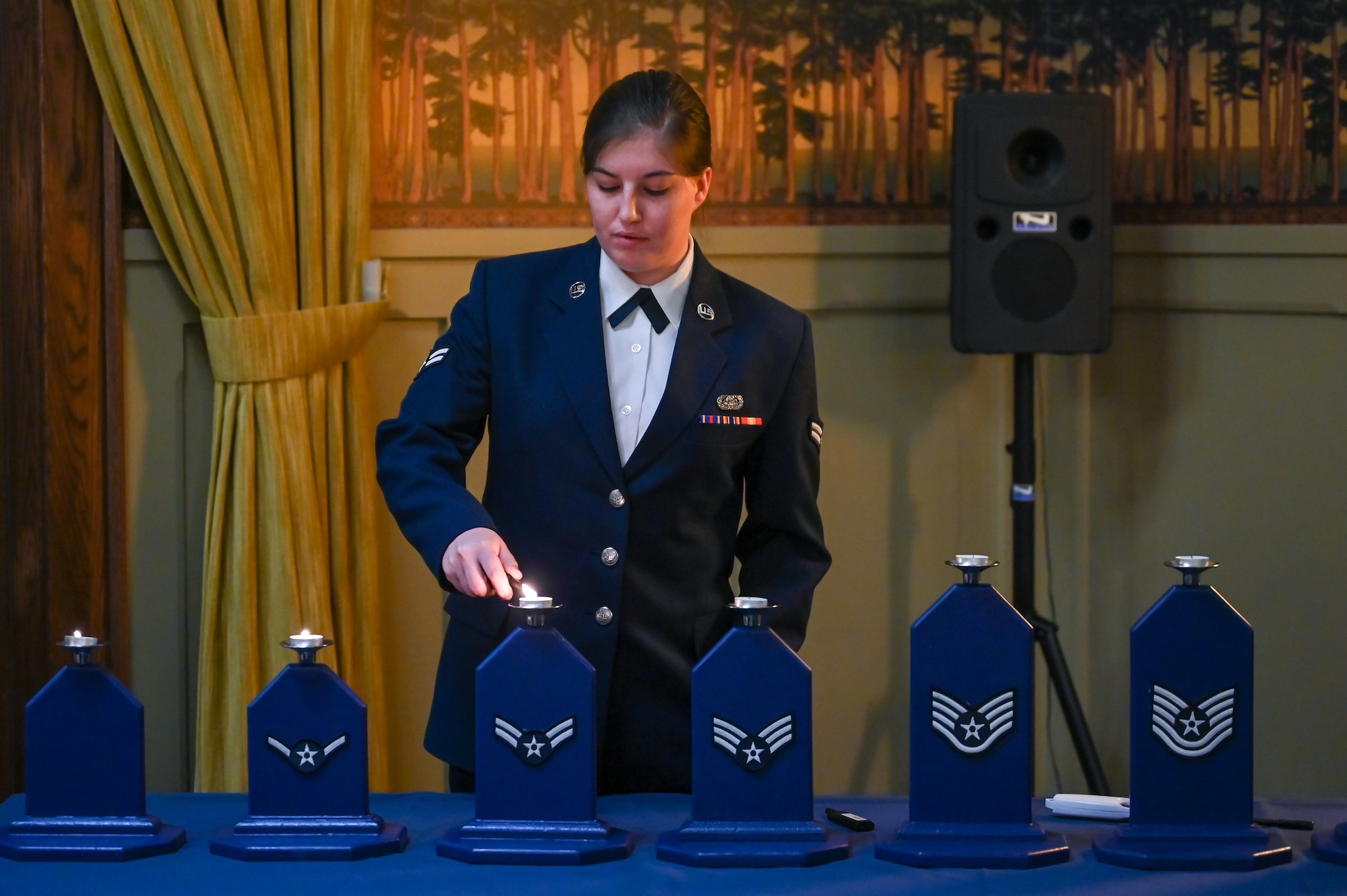 Airman 1st Class Kaeli Schiff, 75th Communications and Information Directorate, lights the candle representing the rank of airman 1st class