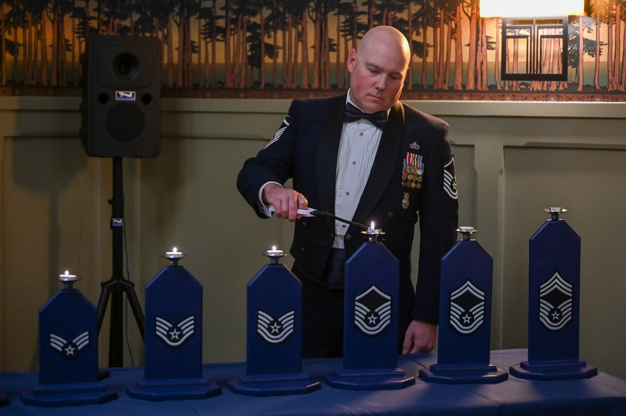Master Sgt. Dustin Krupa, Air Force Life Cycle Management Center, lights the candle representing the rank of master sergeant during Hill Air Force Base's Chief Induction Ceremony