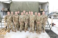 Soldiers assigned to and supporting the 1457th Forward Support Company, 1457th Engineer Battalion, Utah National Guard, stand outside the “CK,” or Containerized Kitchen after preparing the meal for judging during “Final Four” of the Philip A. Connelly Competition at Camp Williams, Utah, February 25, 2023. The Philip A. Connelly Award is given to the best food services organization in the Army. (US Army photo by Sgt. 1st Class Rich Stowell)