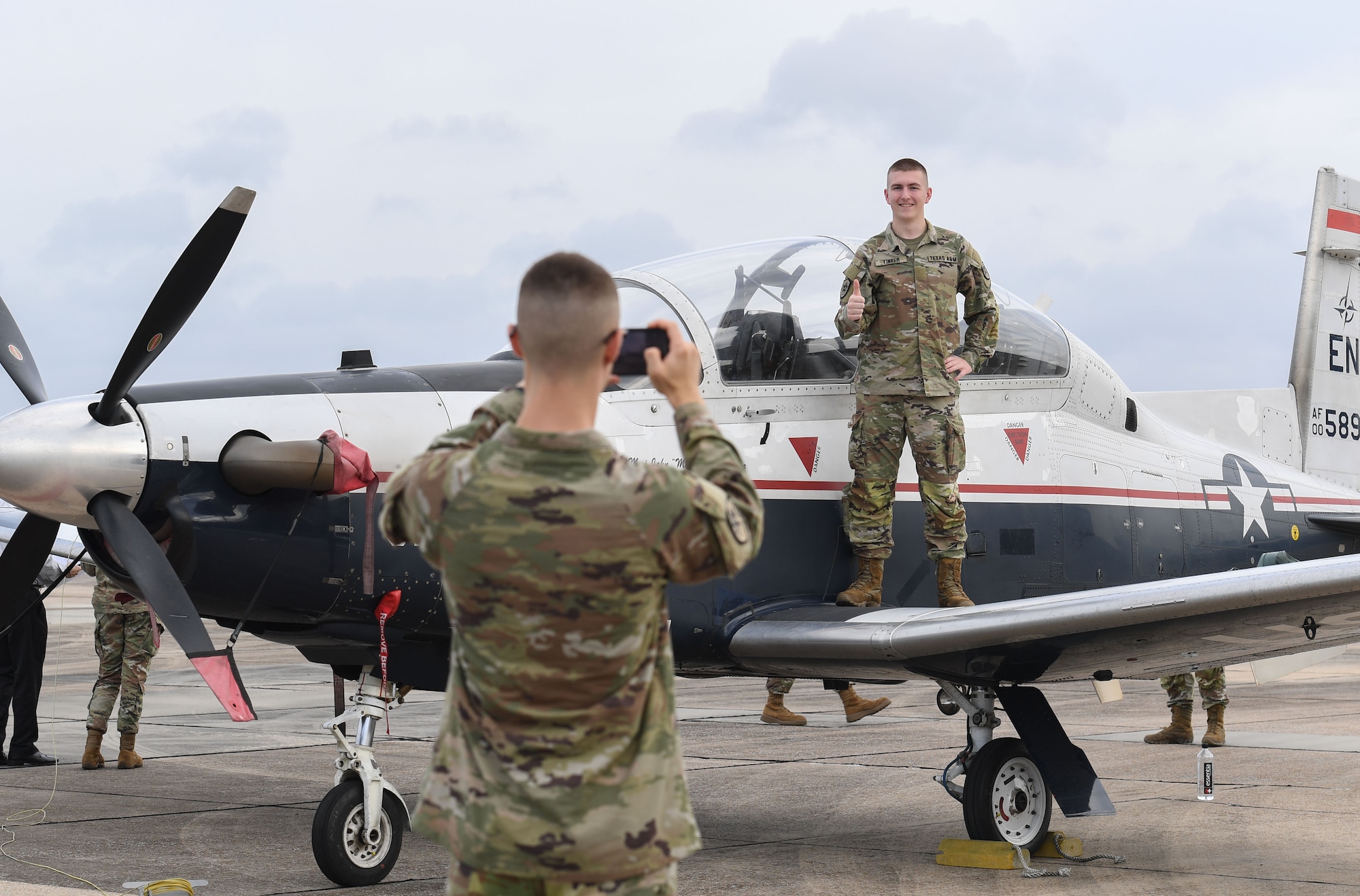 Andrew Tinker, Texas A&M University Air Force ROTC cadet, takes a photo of Kade Lieder, Texas A&M University Air Force ROTC cadet, while standing on the wing of a T-6 Texan during Pathways to Blue at Keesler Air Force Base, Mississippi, March 31, 2023.