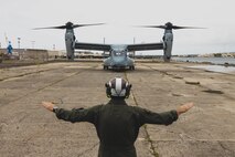 U.S. Marine Corps Gunnery Sgt. Coby Haverkost, a flight line mechanic assigned to Marine Medium Tiltrotor Squadron 363, uses hand and arm gestures to guide an MV-22B Osprey into position at Joint Base Pearl Harbor-Hickam, Hawaii, March 30, 2023. VMM-363 will serve as the Aviation Combat Element for the upcoming iteration of Marine Rotational Force-Darwin. (U.S. Marine Corps photo by Cpl. Brandon Aultman)