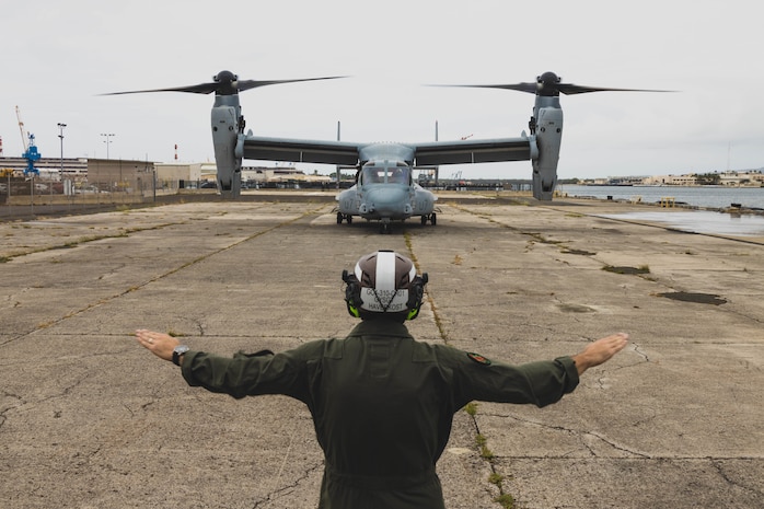 U.S. Marine Corps Gunnery Sgt. Coby Haverkost, a flight line mechanic assigned to Marine Medium Tiltrotor Squadron 363, uses hand and arm gestures to guide an MV-22B Osprey into position at Joint Base Pearl Harbor-Hickam, Hawaii, March 30, 2023. VMM-363 will serve as the Aviation Combat Element for the upcoming iteration of Marine Rotational Force-Darwin. (U.S. Marine Corps photo by Cpl. Brandon Aultman)