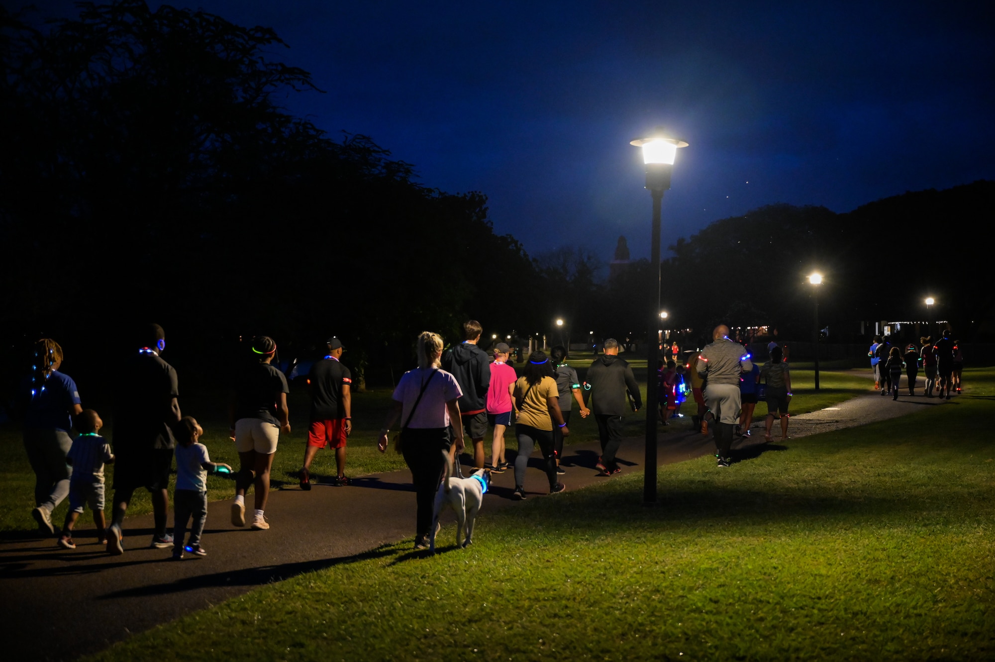 Service members and their families walk and run during a Sexual Assault Awareness Prevention Month glow run at the Missing Man Trail on Joint Base Pearl Harbor-Hickam, Hawaii, Mar. 31, 2023. The run was held to increase awareness of sexual assault within the military and provide helpful resources. (U.S. Air Force photo by Staff Sgt. Alan Ricker)