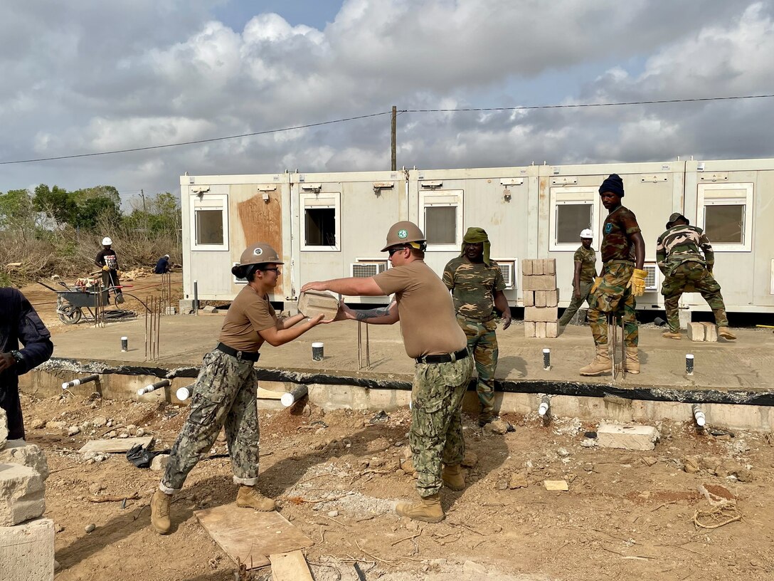 NMCB-1 works with soldiers from the Ghana Army 48 Engineer Regiment to place block for the Danish mobile camp project in Utekpor, Ghana.