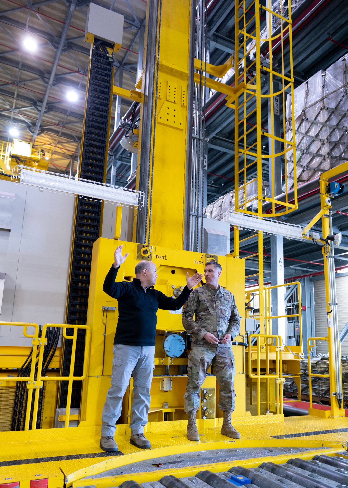 Two men stand on a giant forklift