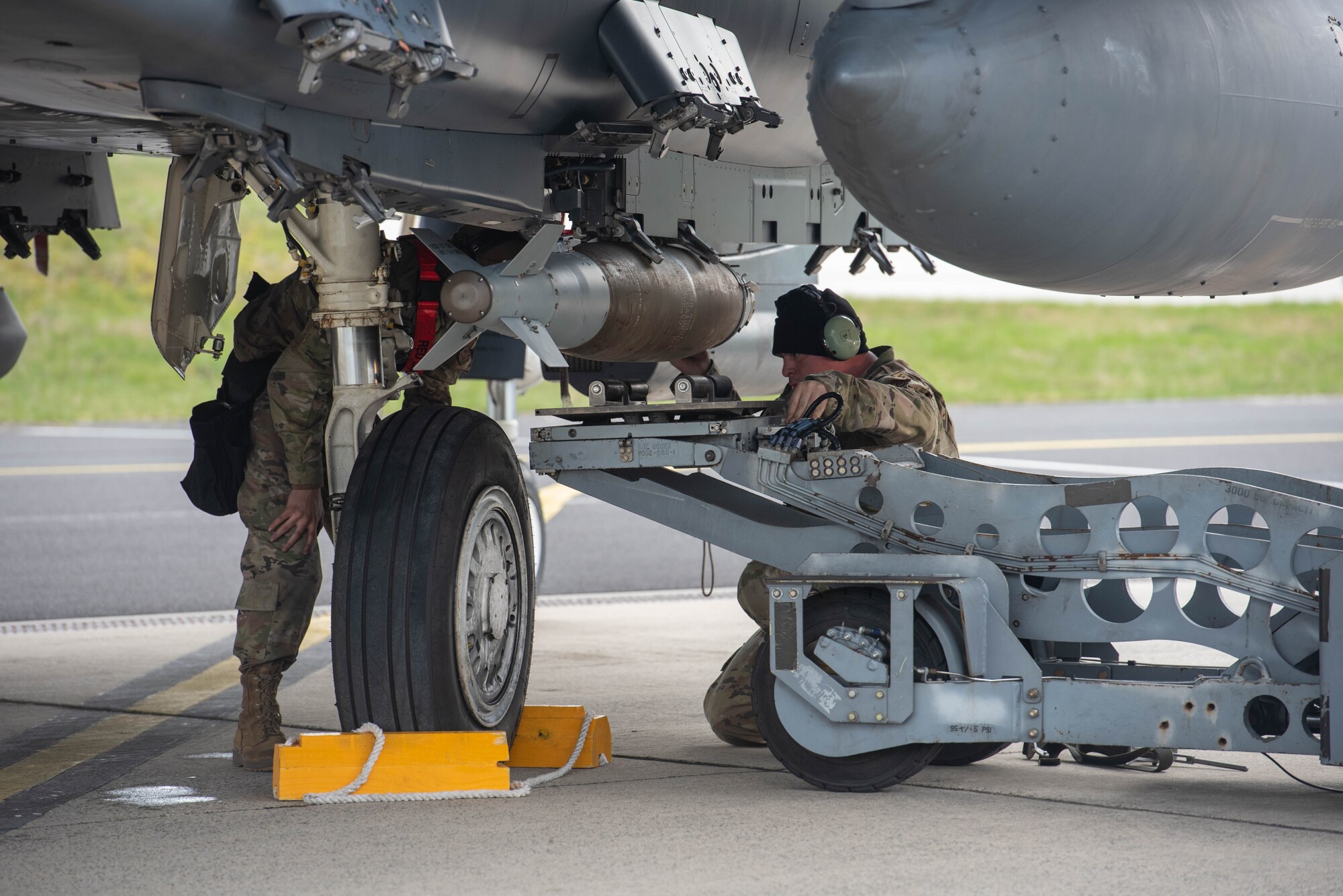 Airmen load live munitions onto an aircraft.