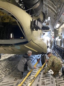 Tracy Mabes, a U.S. Army Aviation and Missile Command Logistics Assistance Representative assigned to the 405th Army Field Support Brigade (left), provides instruction to an Air Force loadmaster at Ramstein Air Base, Germany, during a CH-47 Chinook trans-loading operation after a mechanical issue was discovered in one of the C-17 Globemaster strategic transporters supporting the mission. (U.S. Army Courtesy photo)