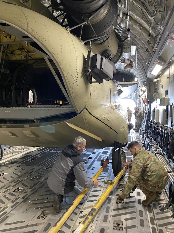 Tracy Mabes, a U.S. Army Aviation and Missile Command Logistics Assistance Representative assigned to the 405th Army Field Support Brigade (left), provides instruction to an Air Force loadmaster at Ramstein Air Base, Germany, during a CH-47 Chinook trans-loading operation after a mechanical issue was discovered in one of the C-17 Globemaster strategic transporters supporting the mission. (U.S. Army Courtesy photo)