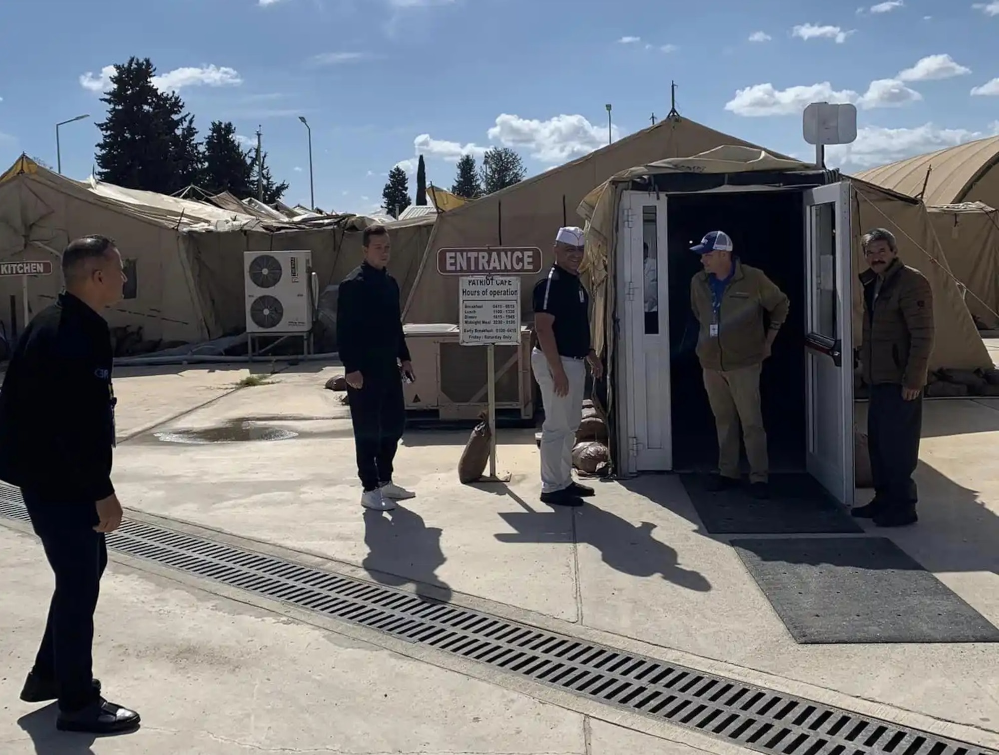 People enter the Patriot Cafe in a field kitchen.