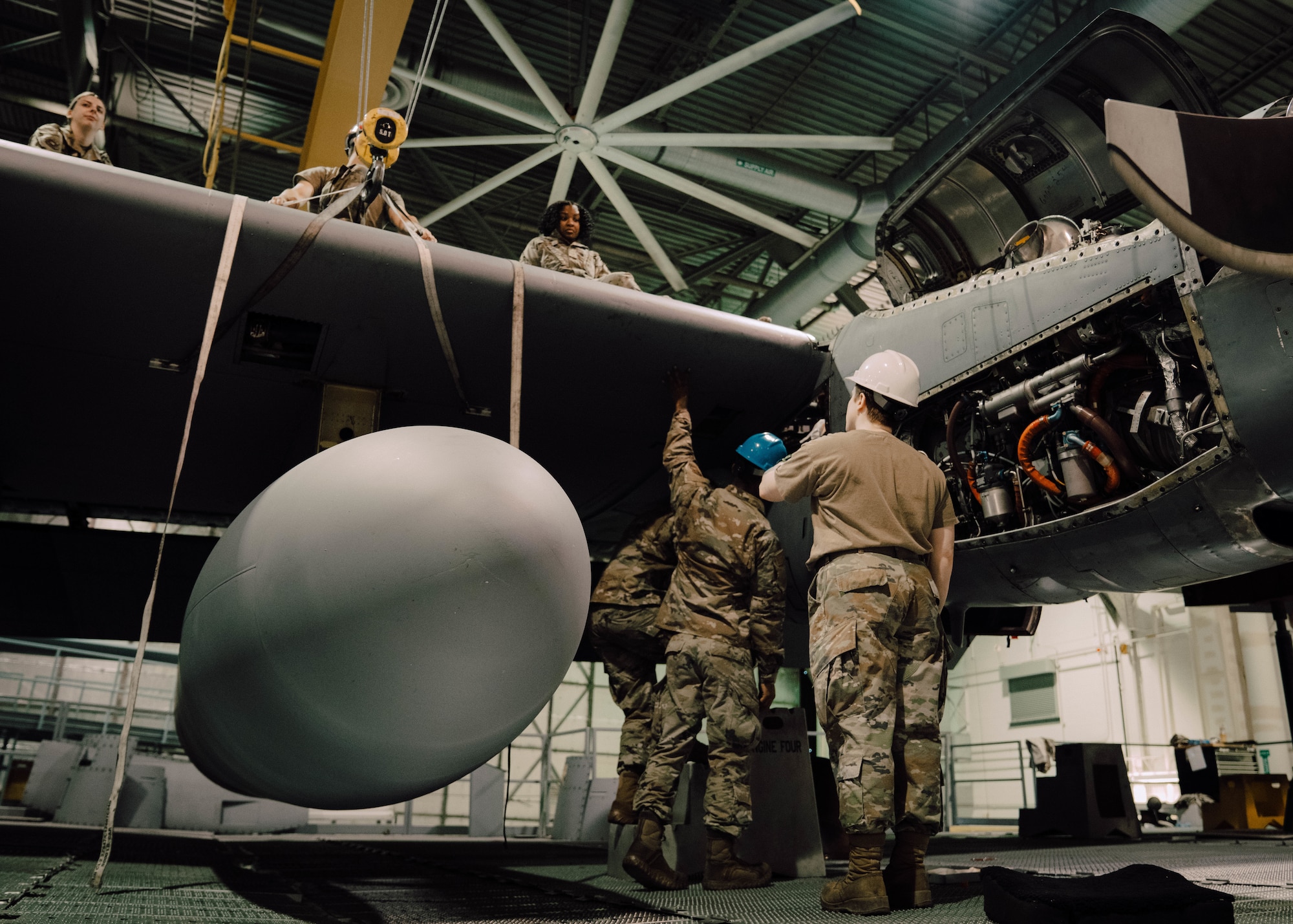 a person in military uniform perform maintenance on an aircraft