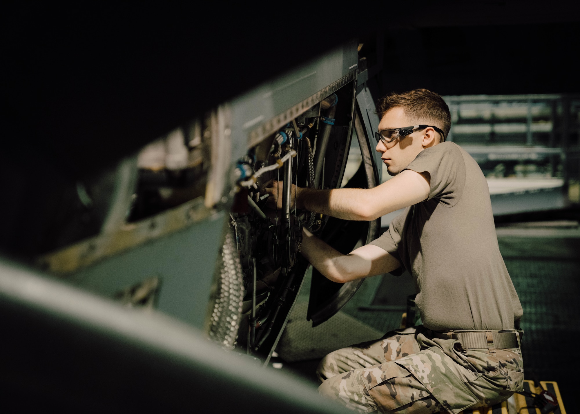 a person in military uniform perform maintenance on an aircraft