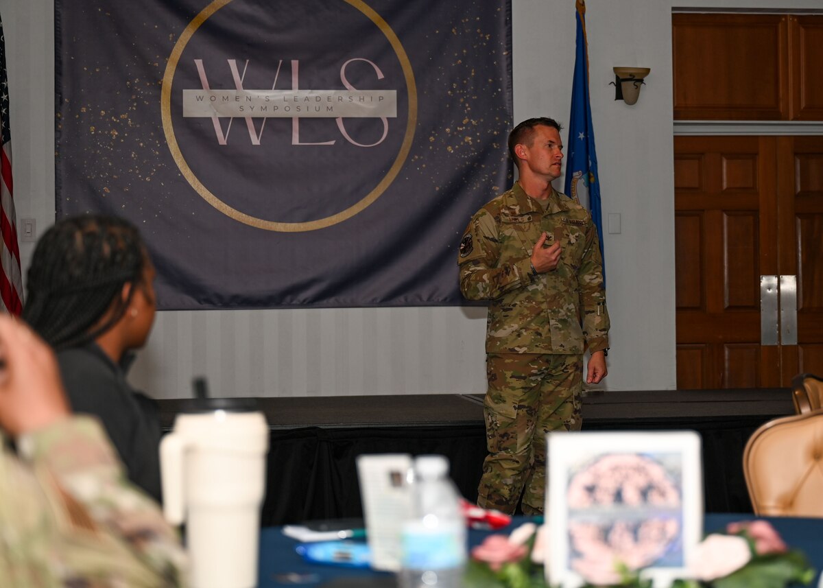 A photo of a man in a military uniform speaking at a symposium.