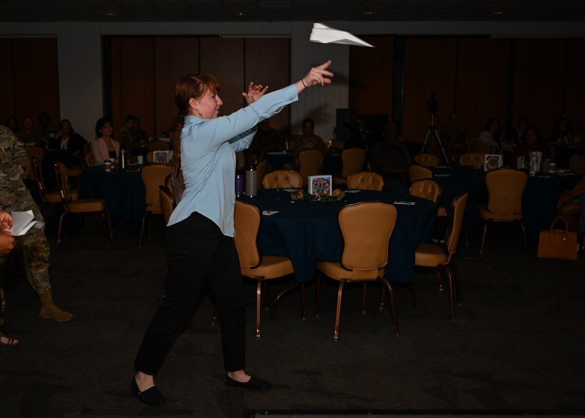 A photo of a woman throwing a paper air plane.