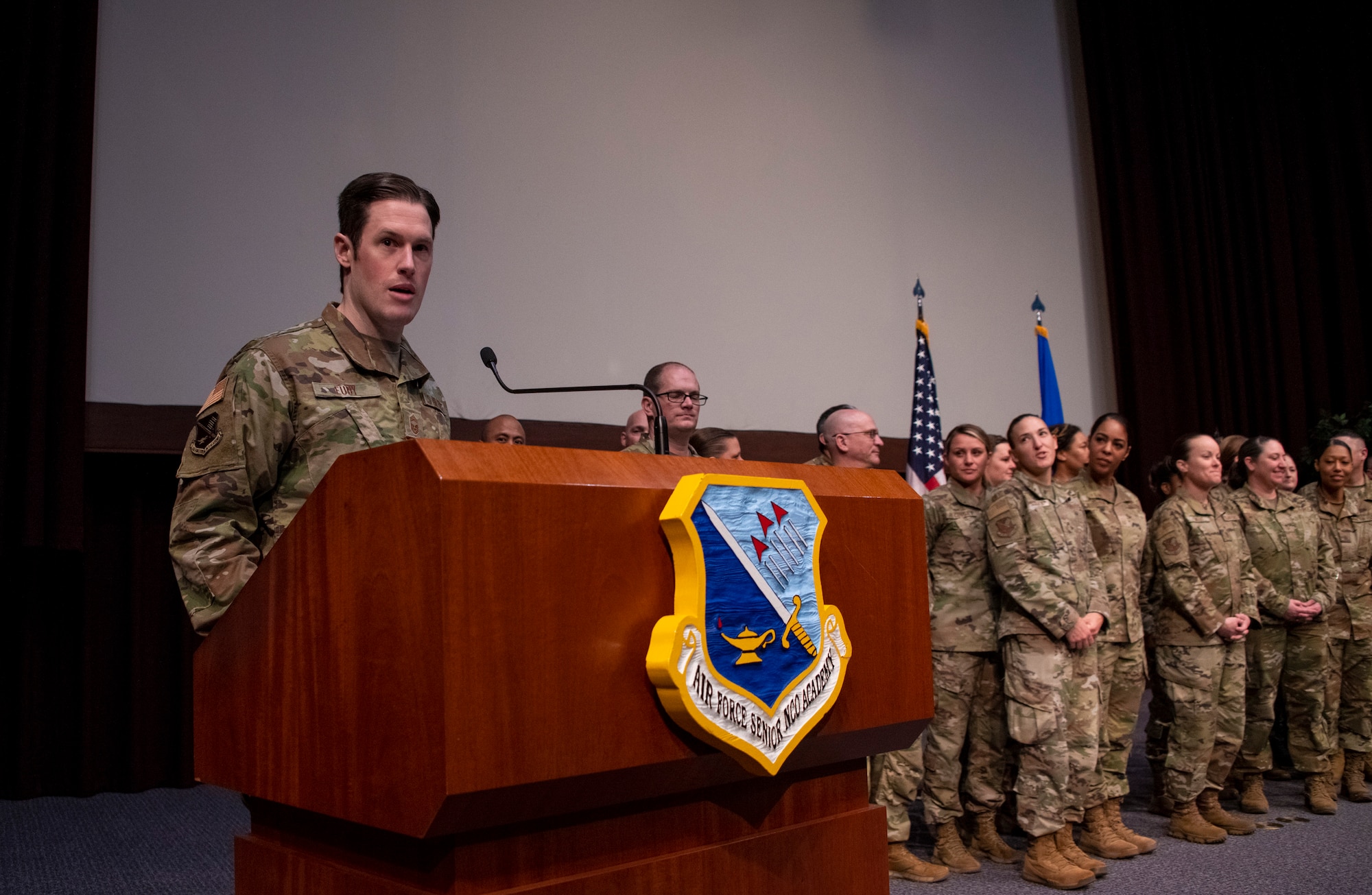 Chief Master Sgt. Alex. J. Eudy, the new Air Force Senior Noncommissioned Officer Academy commandant, speaks as instructors and staff join him on stage during an assumption of leadership ceremony at the academy on Maxwell Air Force Base–Gunter Annex, Ala., March 31, 2023.  Moments later, Air Force Sergeants Association Executive Director Keith Reed presented the instructors and staff with the AFSA Americanism Award for their efforts to develop programs, ceremonies and other initiative that further patriotism in the United States of America. (U.S. Air Force photo/Brian Ferguson)
