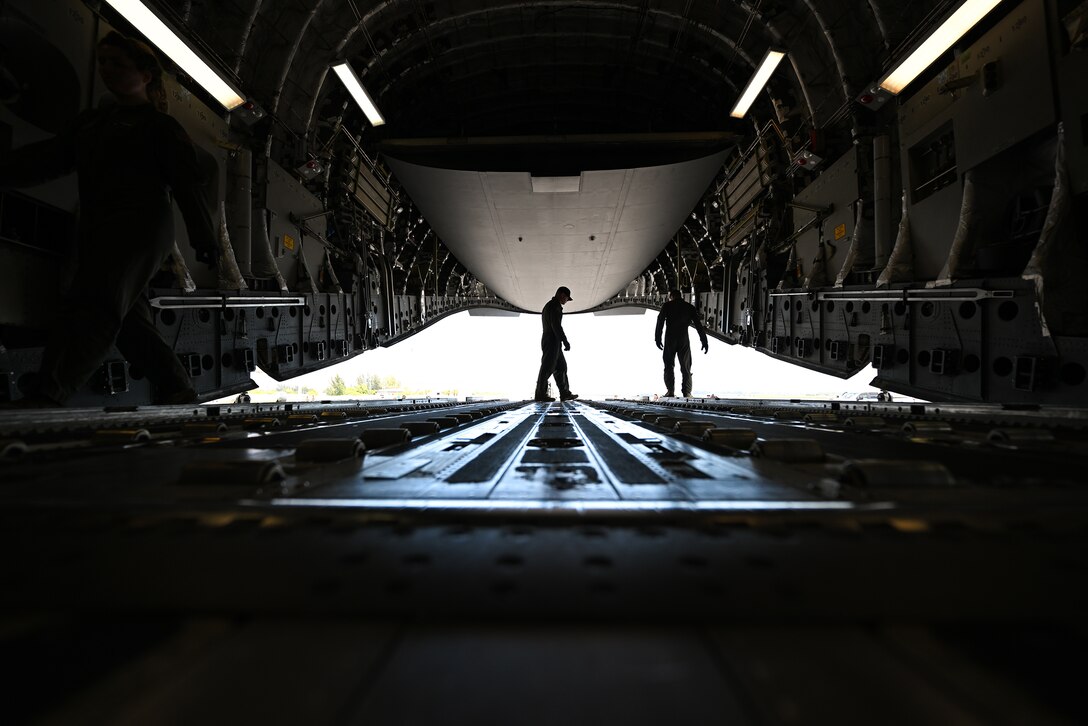 Two airmen stand inside an Air Force aircraft.