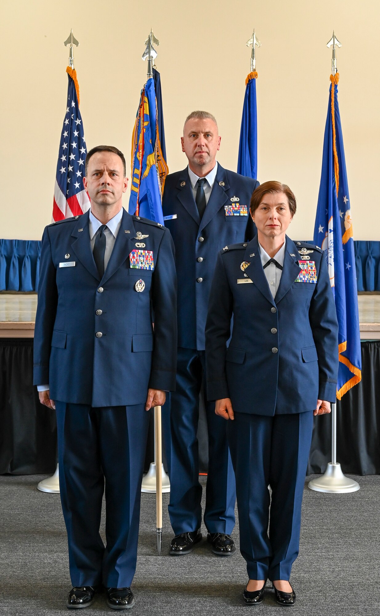 Two men and a woman stand at attention wearing Air Force Dress Blue uniforms.