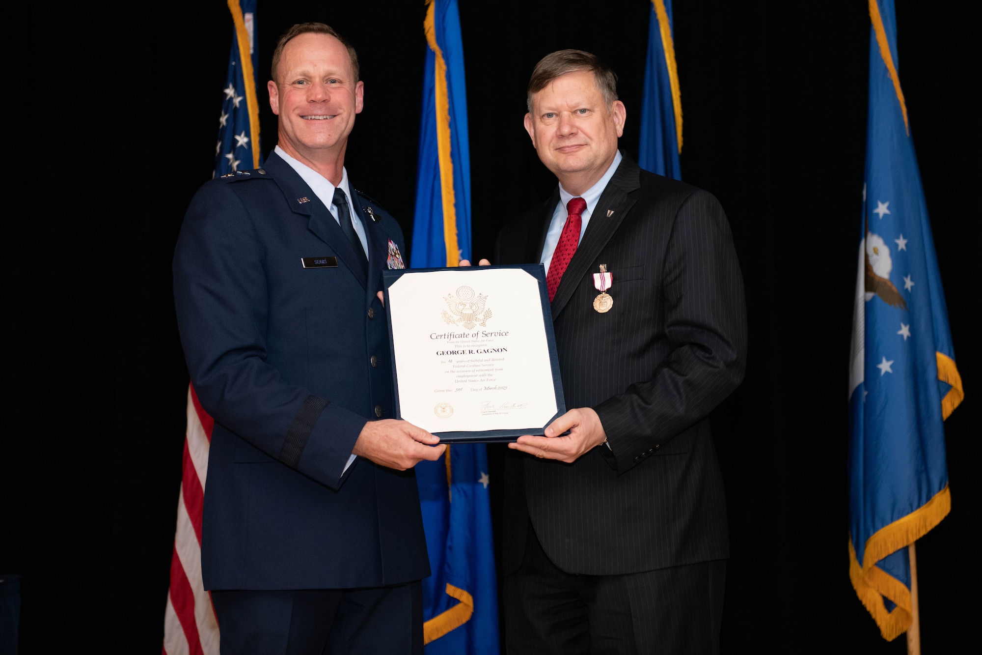 Major General Sears and George Gagnon smile for a photo at the retirement ceremony of Gagnon.