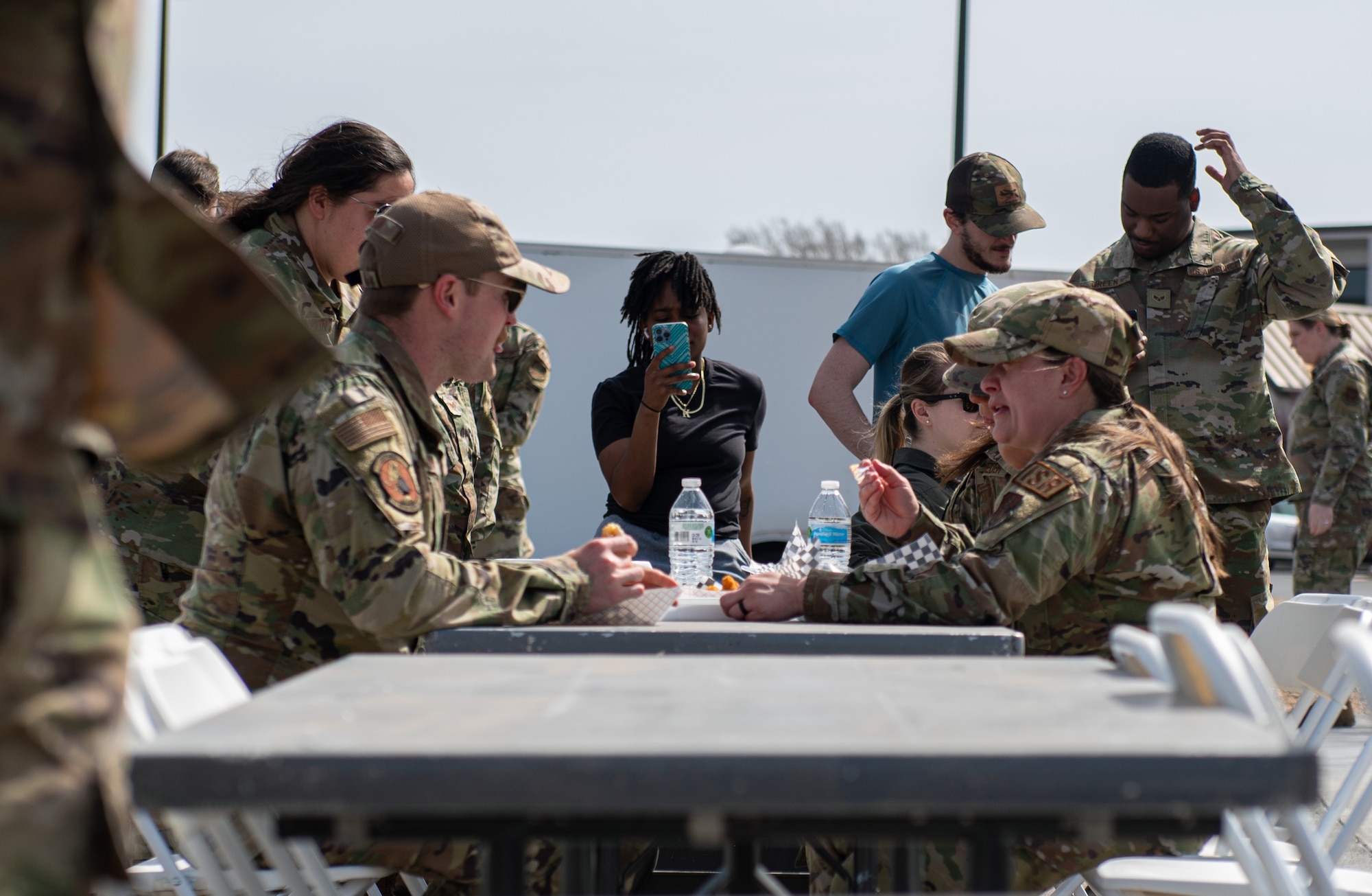 Team McConnell Airmen eat lunch at the grand opening for the food truck park at McConnell Air Force Base, Kansas, April 4, 2023. The food truck park provides a variety of easily accessible food for Team McConnell servicemembers. The area was designated a no hat, no salute area for the grand opening. (U.S. Air Force photo by Staff Sgt. Tryphena Mayhugh)