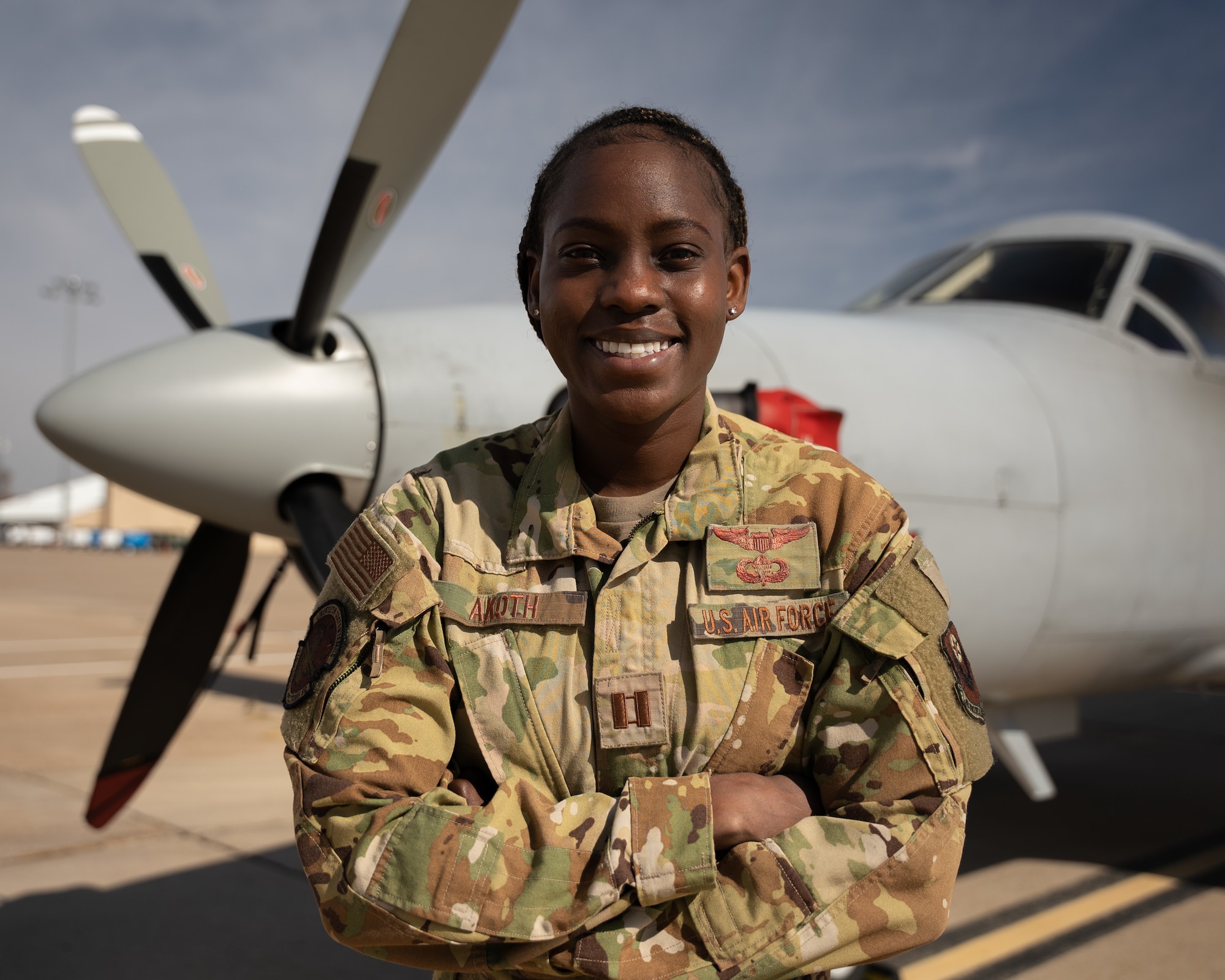A female airman poses in front of an aircraft.