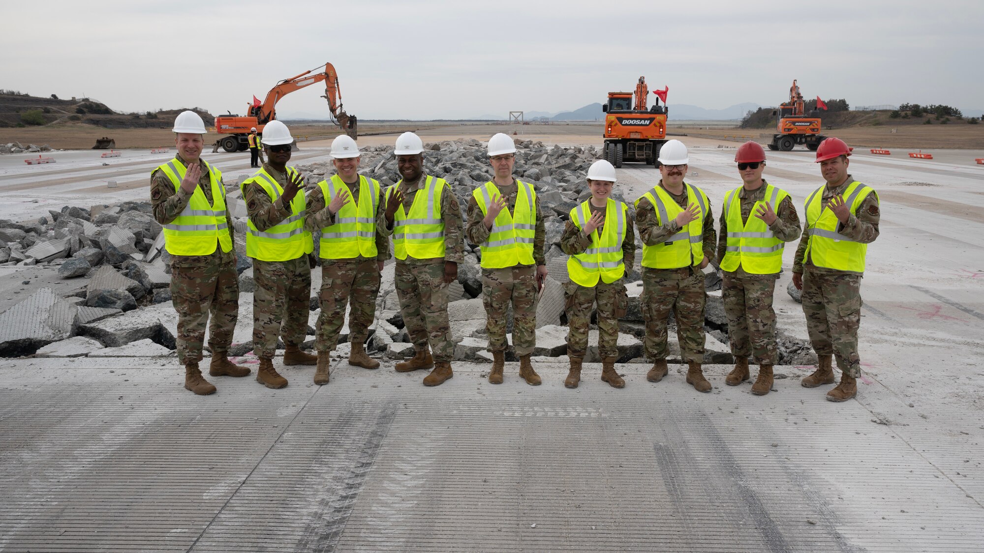 A group of leadership Airmen pose for a photo while displaying an 8th Civil Engineer Squadron heritage gesture.