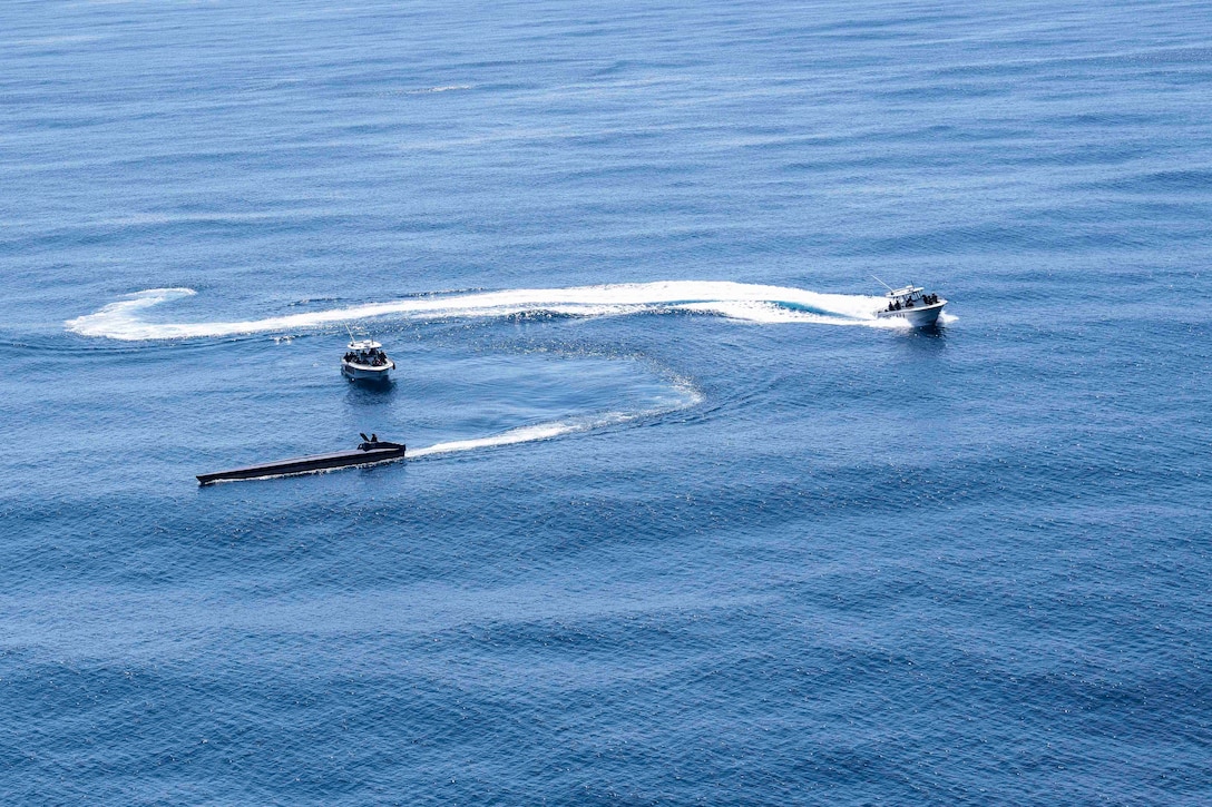 Three vessels move through a body of water.