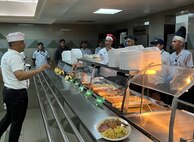 Team members stand behind a food line ready for service.
