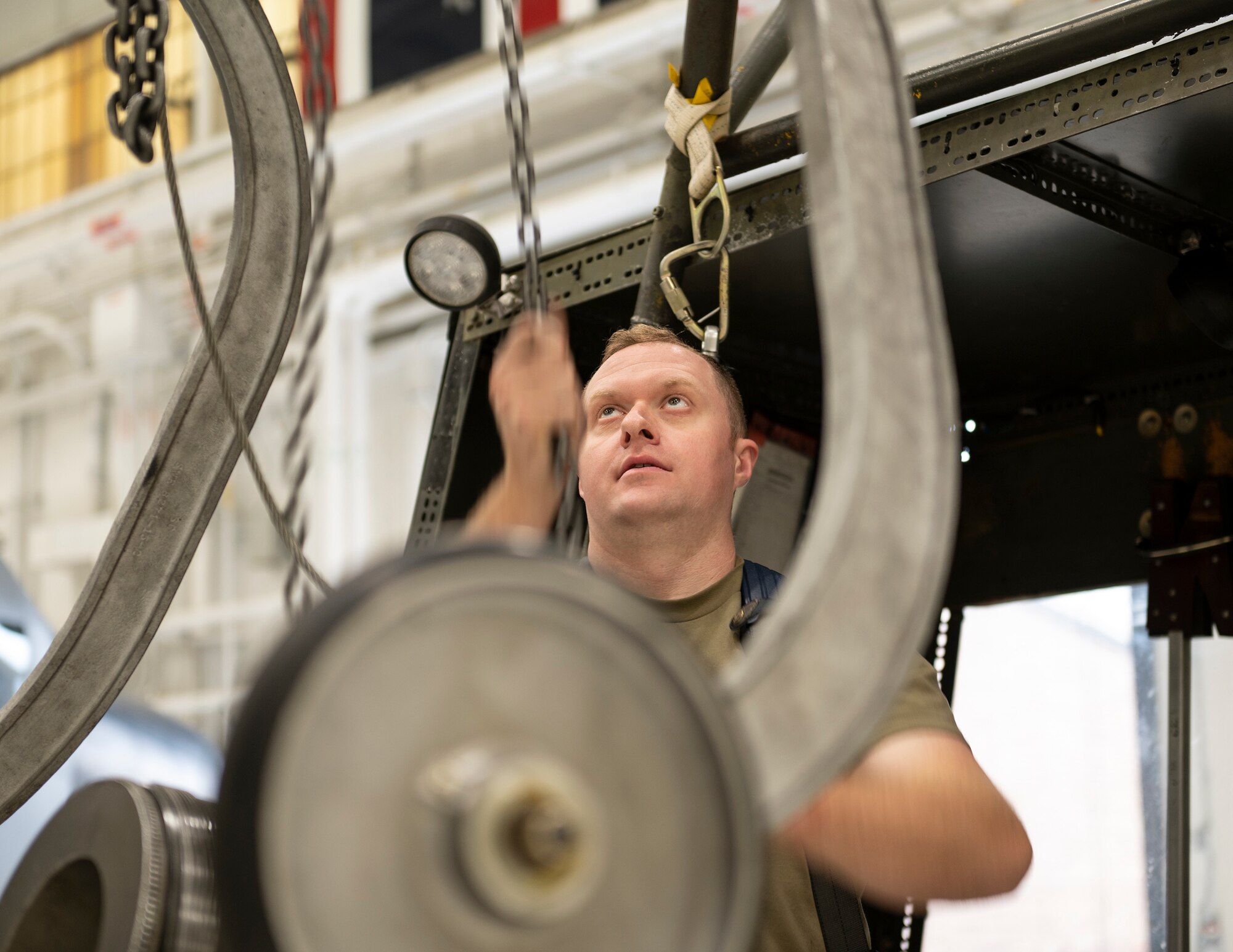 U.S. Air Force Tech. Sgt. Luke Harren, propulsion mechanic, 133rd Maintenance Squadron, moves a chain hoist into position in St. Paul, Minn., Oct. 24, 2022.
