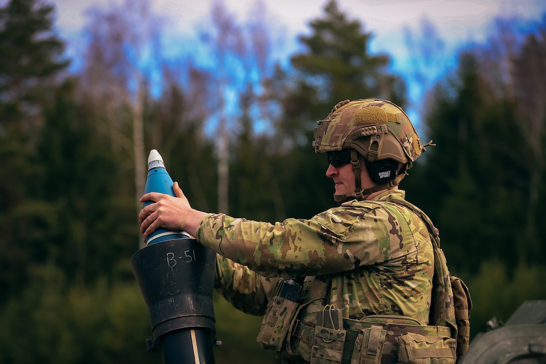 A soldier loads a mortar into a cylinder.