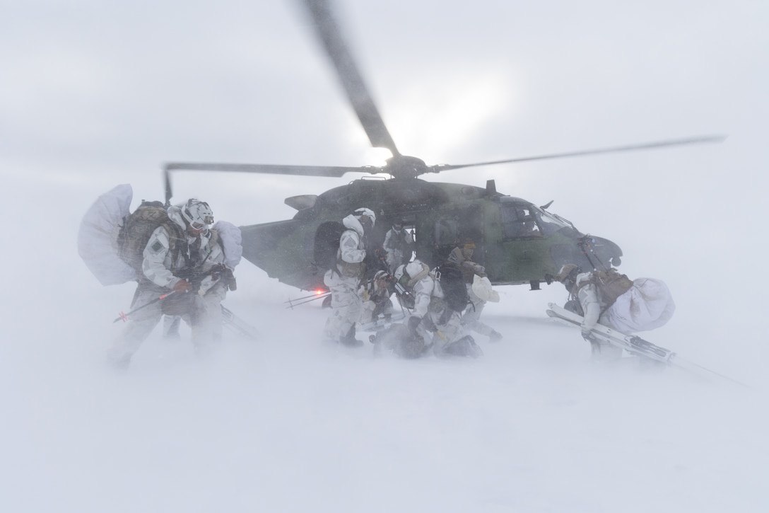 Green Berets get into a helicopter under snowy conditions.