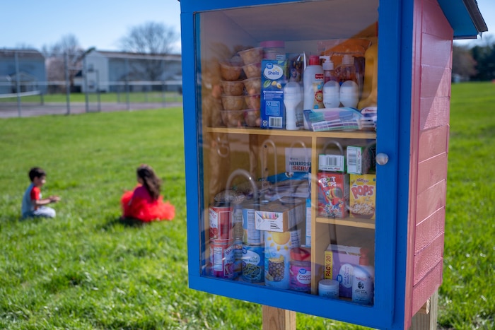 Two kids play near a box filled with food