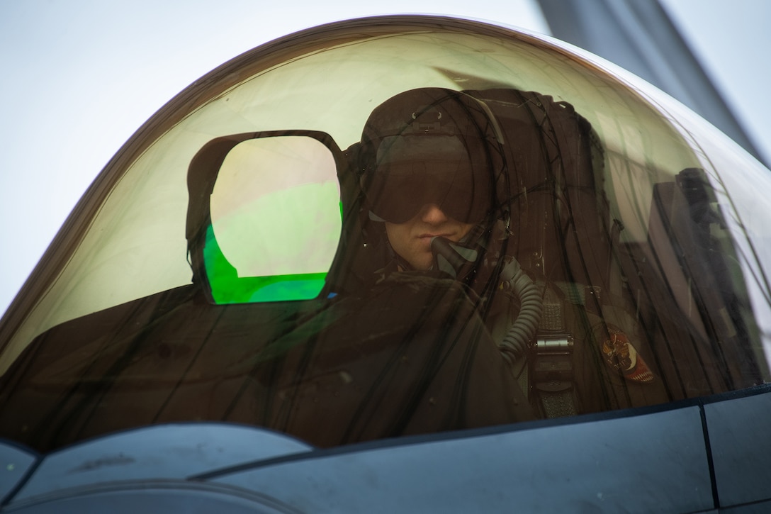 An airman is photographed in the cockpit of an Air Force aircraft.