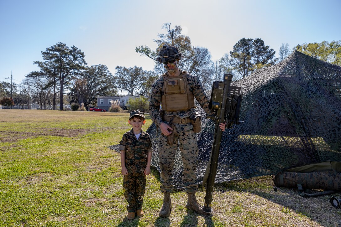 U.S. Marine Corps Cpl. Tyler Steigler, a low altitude air defense gunner with 2nd Low Altitude Air Defense Battalion (LAAD), poses for a picture with a student at Oaks Road Elementary in New Bern, North Carolina, March 24, 2023. 2nd LAAD and to Marine Wing Support Squadron (MWSS) 271 participated in a career fair at Oaks Road Elementary School to strengthen rapport with the local community. 2nd LAAD and MWSS-271 are subordinate units of 2nd Marine Aircraft Wing, the aviation combat of II Marine Expeditionary Force. (U.S. Marine Corps photo by Cpl. Caleb Stelter)