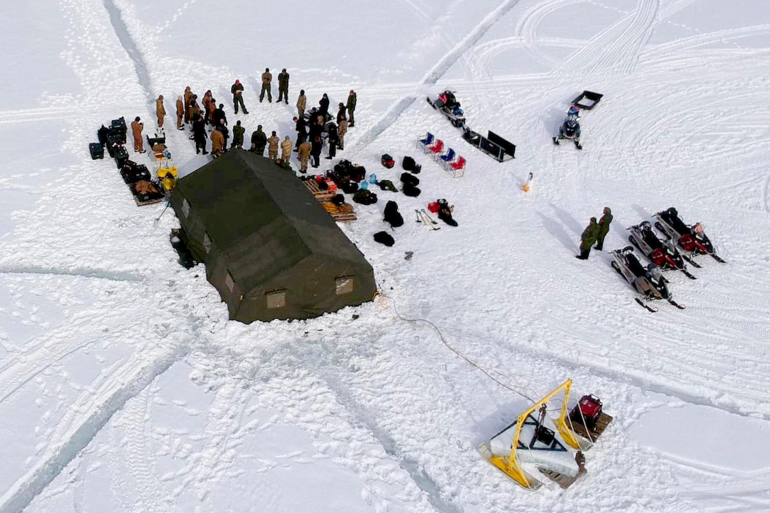 An aerial view of service members at a camp site in the snow.