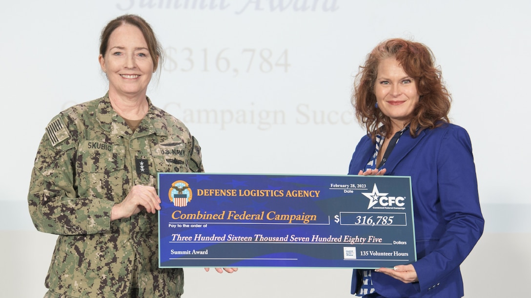 Two women hold a large check.