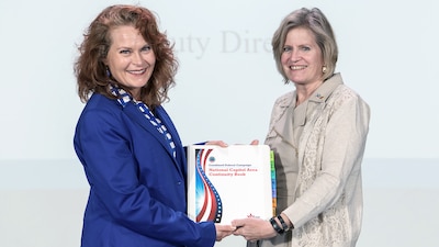 Two women hold a book between them.