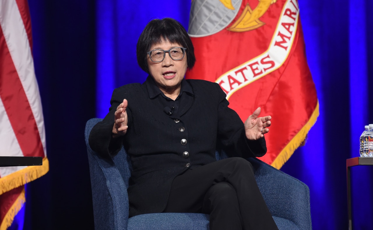 A woman appears to speak as she gestures with her hands.