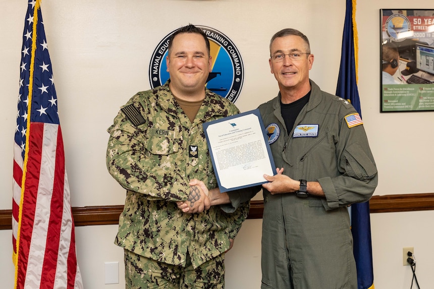 Rear Adm. Pete Garvin, right, commander, Naval Education and Training Command (NETC), presents Culinary Specialist 1st Class Evan Kern, NETC Pensacola’s enlisted aide, with a flag letter of commendation for his selection as NETC’s 1st Qtr. fiscal year 2023 senior Sailor of the quarter during an awards ceremony in Pensacola, Fla., March 28, 2022. NETC’s mission is to recruit, train and deliver those who serve our nation, taking them from street-to-fleet by forging civilians into highly skilled, operational and combat ready warfighters. (U.S. Navy photo by Mass Communication Specialist 2nd Class Zachary Melvin)