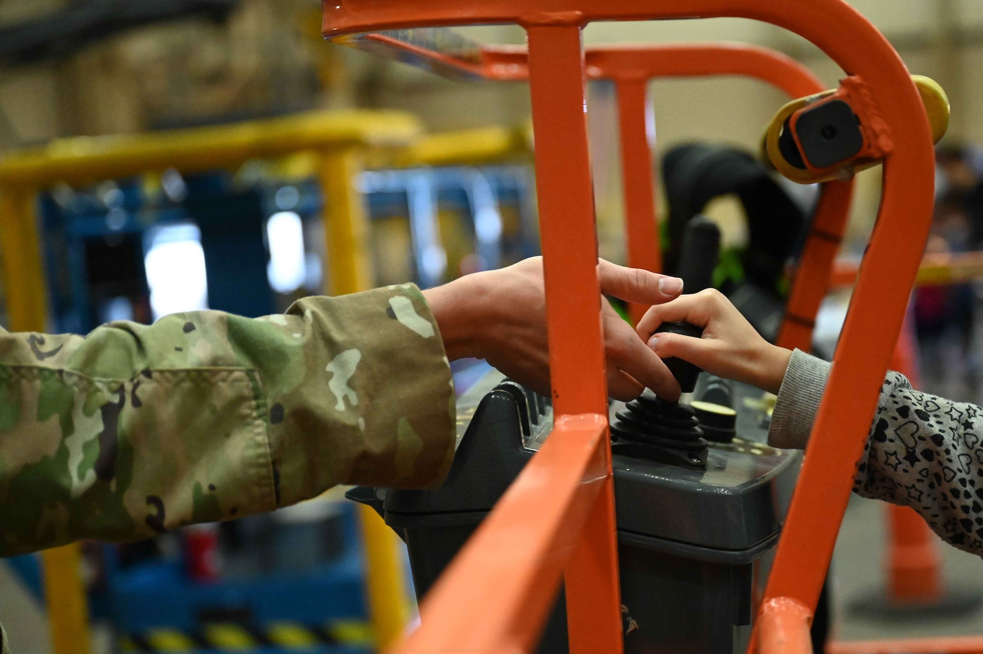 U.S. Air Force Airman 1st Class Blake Silvis, 97th Civil Engineering Squadron structure shop Airman, shows a child how to operate a boom lift during the “Kid’s Deployment Line” at Altus Air Force Base, Oklahoma April 1, 2023. The kids were able to get into fire trucks, police cars, and a C-17 Globemaster III throughout the event. (U.S. Air Force photo by Airman 1st Class Kari Degraffenreed)