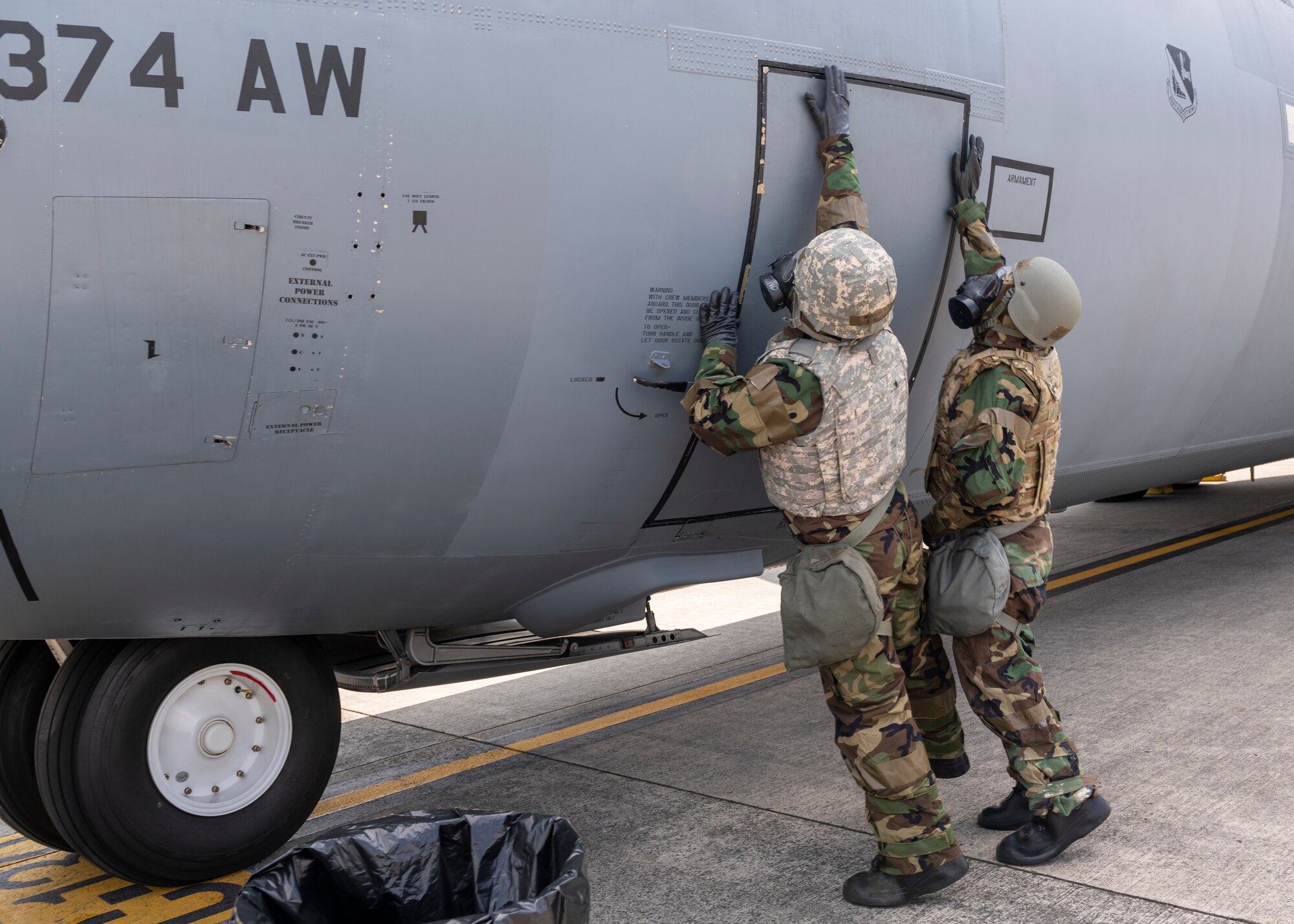 Two airmen in HAZMAT suits open an aircraft door